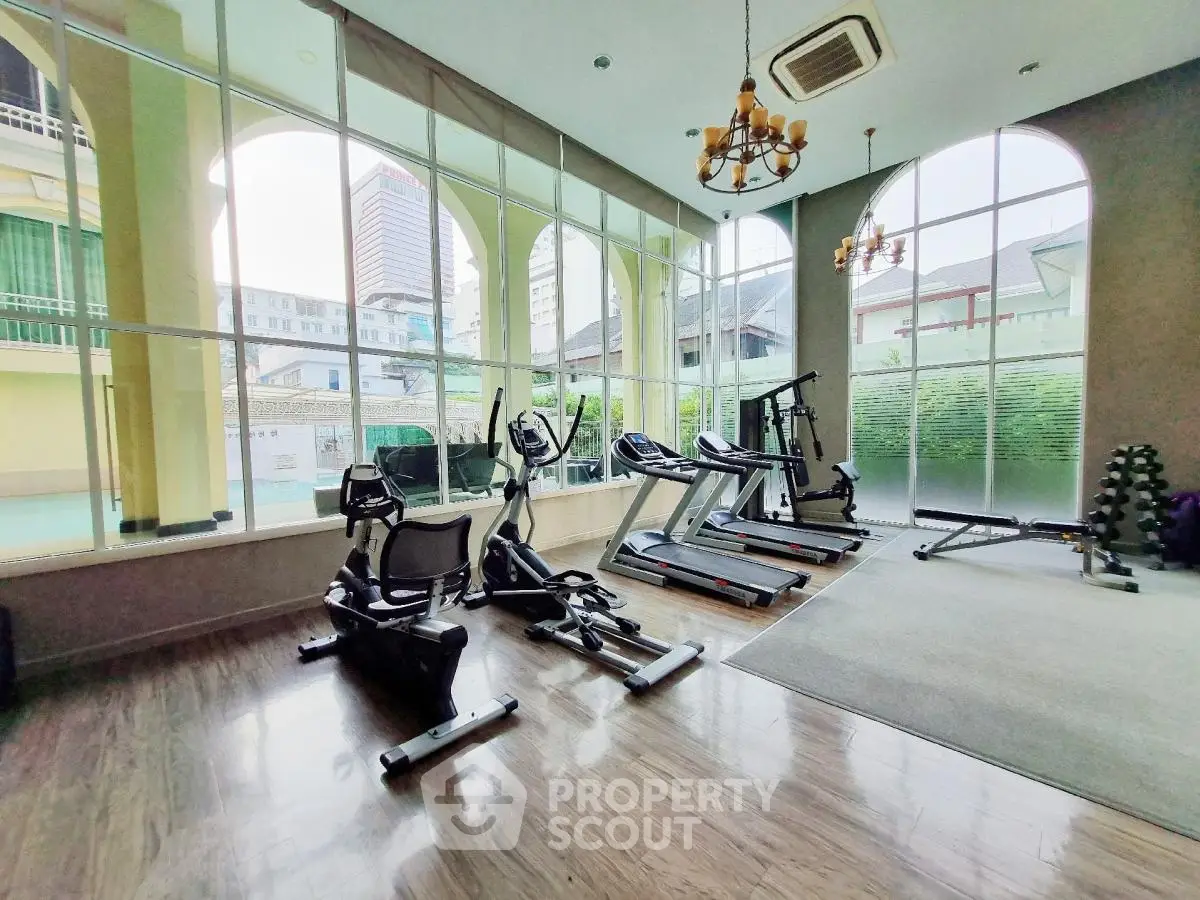 Modern gym with large windows and exercise equipment in luxury real estate property.
