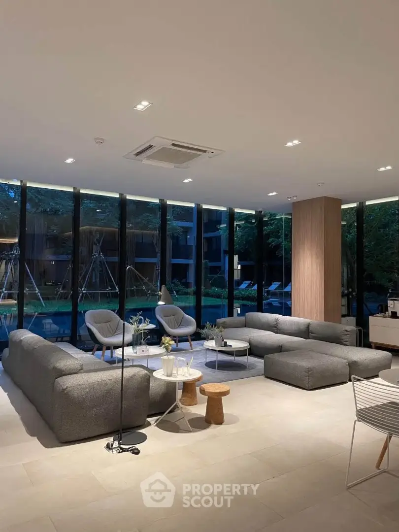 Luxurious modern living room with large windows overlooking a serene garden, featuring stylish gray sofas and chic decor.
