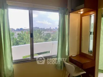 Cozy bedroom with vanity and scenic window view in urban setting