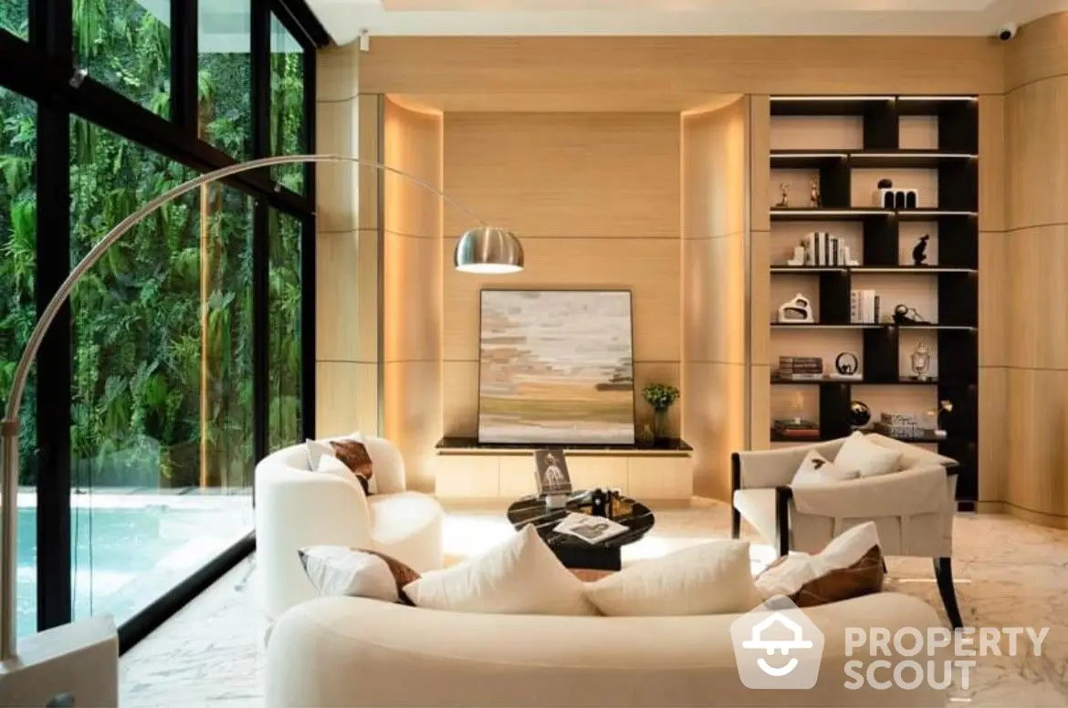 Luxurious living room with modern furnishings, warm ambient lighting, and a view of a serene outdoor pool area, perfect for upscale living.