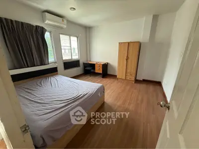 Spacious bedroom with wooden flooring and modern furniture