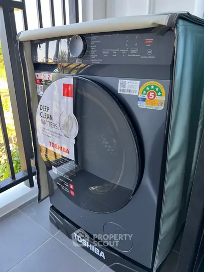 Modern Toshiba washing machine on a balcony with sleek design and energy efficiency rating.