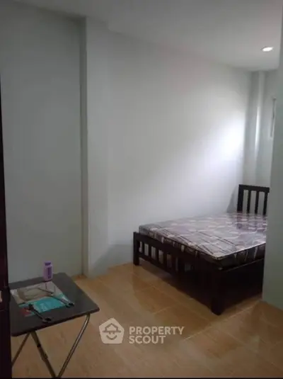 Cozy minimalist bedroom with wooden bed frame and small table, perfect for urban living.