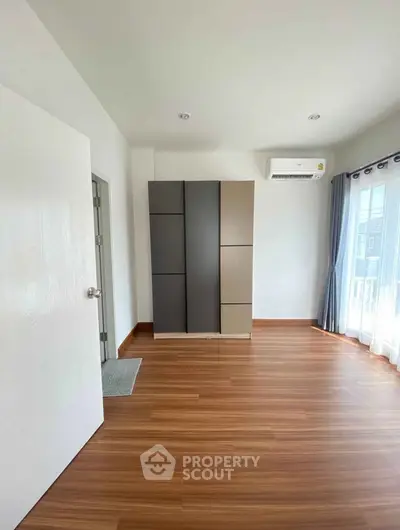 Spacious bedroom with modern wardrobe and natural light from large windows.