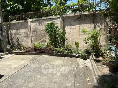 Charming garden area with lush greenery and concrete pathway, perfect for outdoor relaxation.