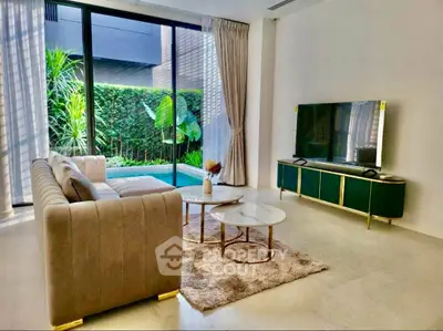Luxurious living room with modern decor and pool view, featuring elegant furniture and large windows.