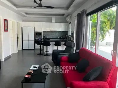 Modern open-layout living room with sleek kitchen and vibrant red sofa, perfect for stylish living.