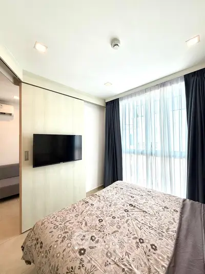 Modern bedroom with large window and wall-mounted TV in a stylish apartment.