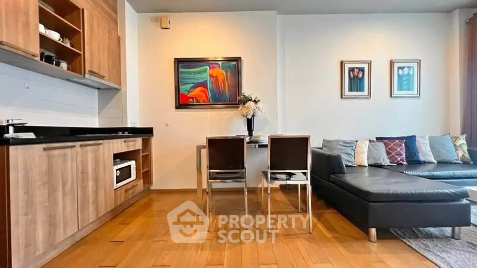 Modern living room with open kitchen, wooden flooring, and stylish decor in a cozy apartment.