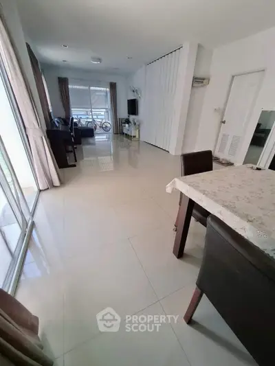 Spacious modern living room with large windows and elegant dining area