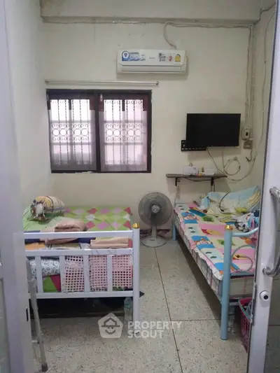 Cozy bedroom with twin beds, air conditioning, and wall-mounted TV, perfect for small living spaces.