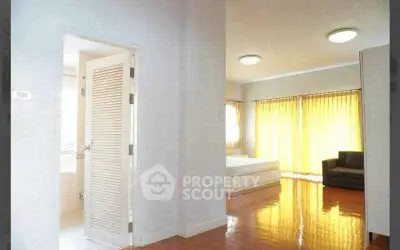 Spacious bedroom with glossy wooden floors and ample natural light
