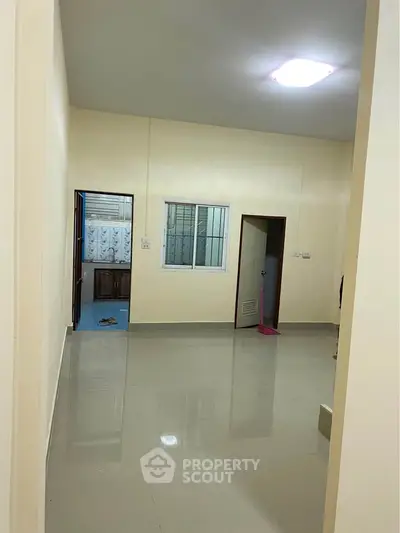 Spacious unfurnished room with glossy tiled flooring and neutral walls, ideal for customization.