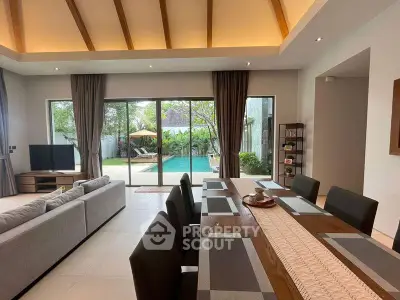 Luxurious open-plan living room with pool view, high ceilings, and elegant dining area in modern villa.