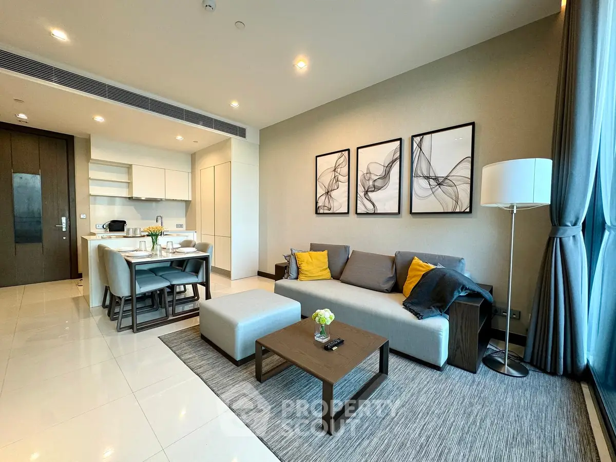 Modern open-layout living room with stylish decor and kitchen area, featuring neutral tones and elegant furnishings.