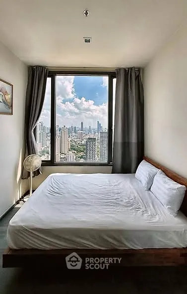 Modern bedroom with stunning city view through large window, featuring a cozy bed and elegant decor.
