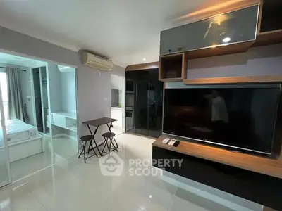 Modern living room with sleek TV setup and dining area in stylish apartment