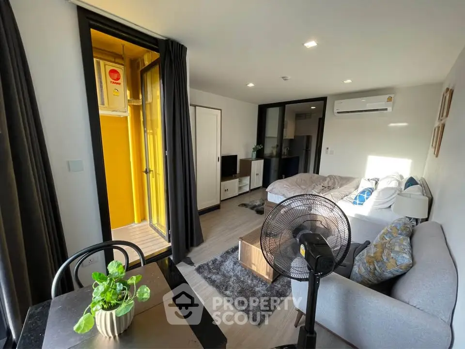 Modern living room with cozy sofa, dining area, and balcony access in stylish apartment.