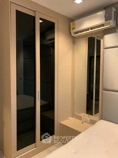 Modern bedroom with mirrored wardrobe and air conditioning unit