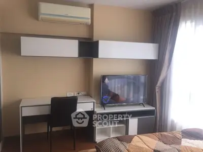 Modern bedroom with sleek desk, wall-mounted storage, and flat-screen TV near a large window.