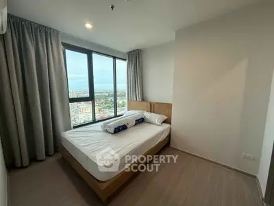 Modern bedroom with large window offering stunning city views in high-rise apartment.