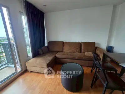 Cozy living room with brown sectional sofa and city view balcony, perfect for relaxation.