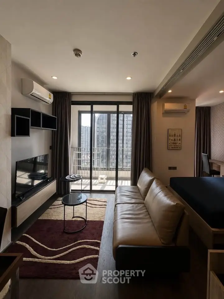 Modern living room with leather sofa, TV, and balcony view in high-rise apartment.