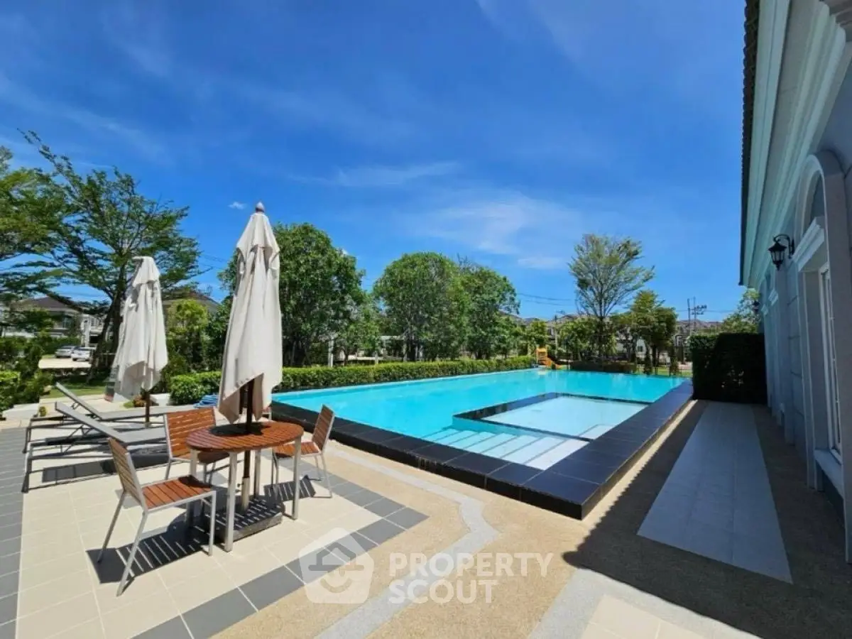 Stunning outdoor pool area with seating and lush greenery, perfect for relaxation.