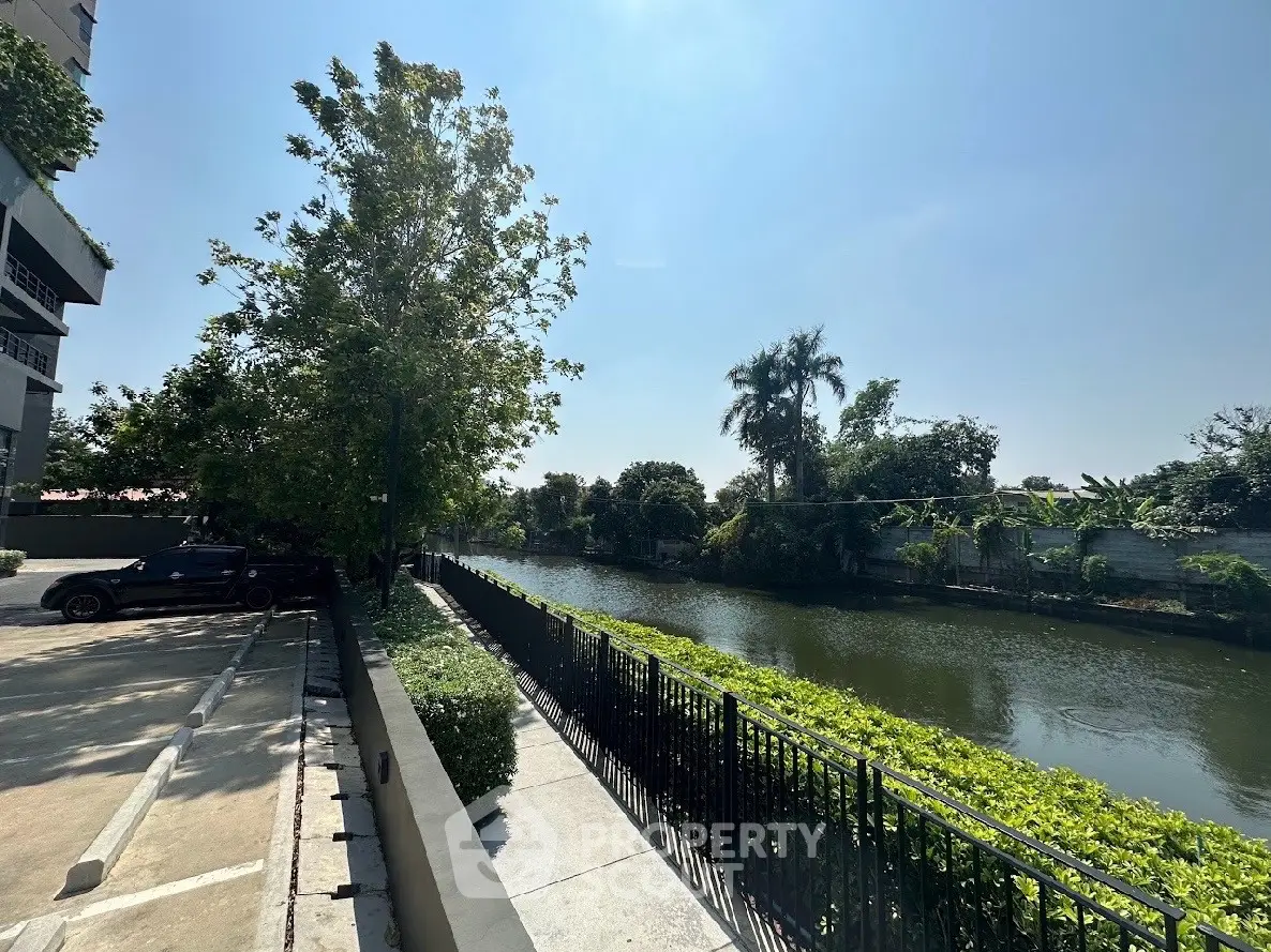 Scenic riverside view from a residential building with lush greenery and clear blue sky.