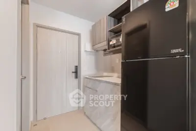 Modern compact kitchen with sleek cabinetry and black refrigerator in a stylish apartment.