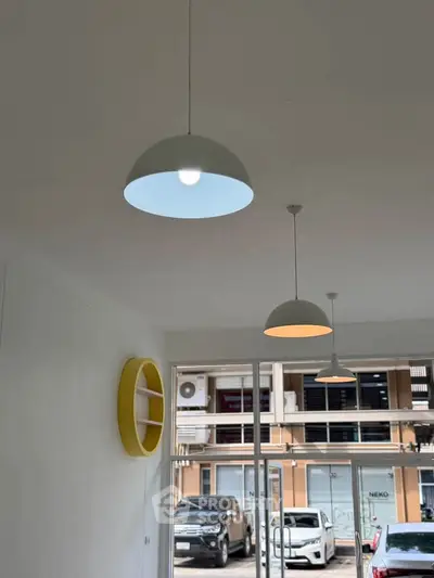 Modern interior with stylish pendant lights and large windows overlooking urban street view.