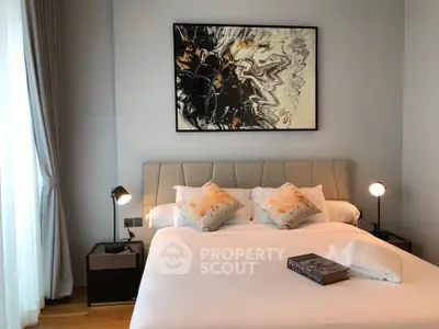 Elegant bedroom with modern decor and stylish artwork above the bed, featuring cozy lighting and plush pillows.
