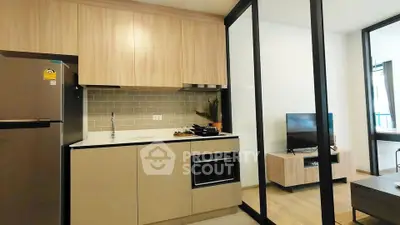 Modern kitchen with sleek cabinetry and open layout adjacent to cozy living area.