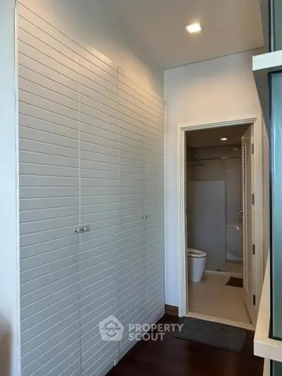 Modern bathroom with sleek design and ample storage space, featuring a contemporary toilet and elegant finishes.