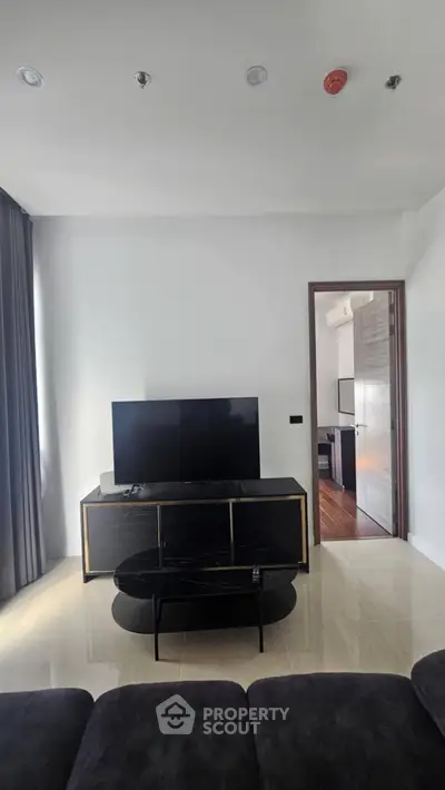 Modern living room with sleek TV stand and large flat-screen TV, featuring elegant decor and natural light.