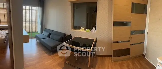 Modern apartment interior with sleek living room and bedroom, featuring stylish furniture and wooden flooring.