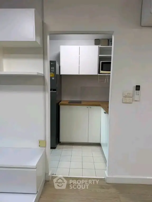 Compact kitchen with modern appliances and sleek cabinetry in a cozy apartment setting.