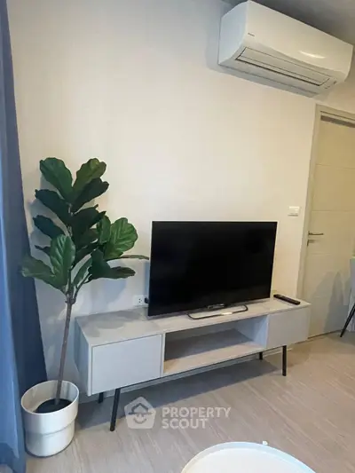 Modern living room with TV, air conditioner, and indoor plant for cozy ambiance.