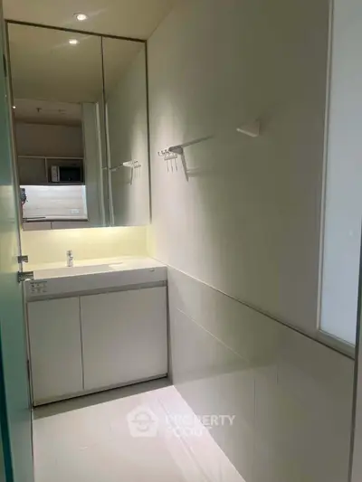 Modern bathroom with sleek design and ample lighting, featuring a large mirror and minimalist fixtures.