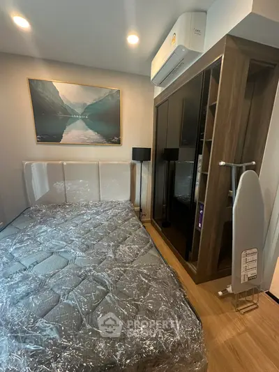 Modern bedroom with sleek furniture and air conditioning, featuring a stylish wardrobe and ironing board.