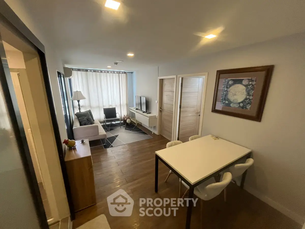 Modern living room with stylish decor and dining area, featuring wooden flooring and ample natural light.