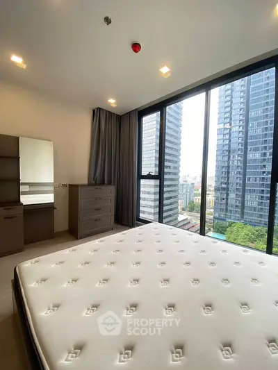 Modern bedroom with large windows offering stunning city views in a high-rise apartment.