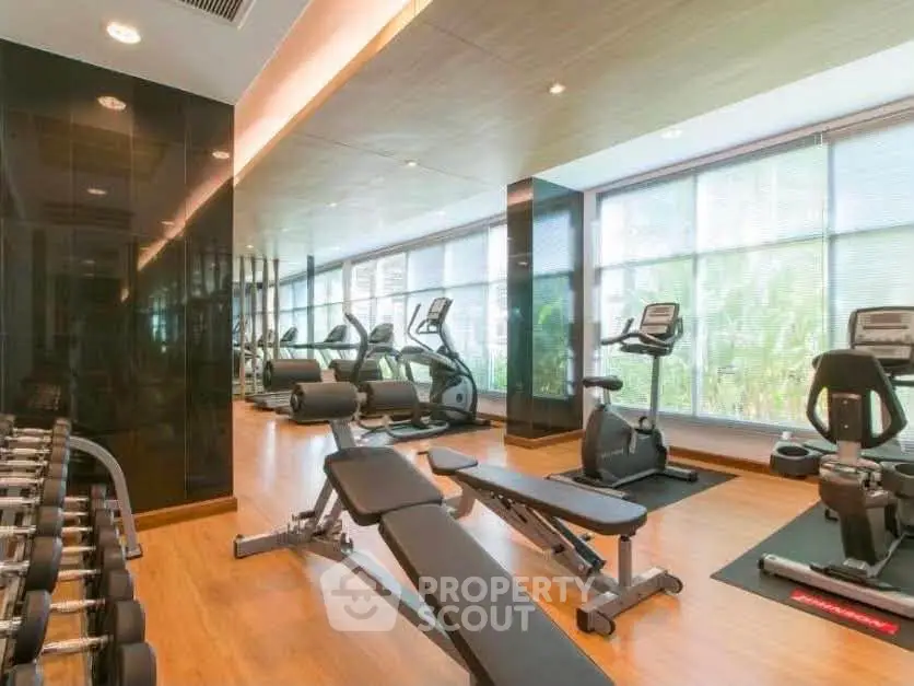 Modern gym with state-of-the-art equipment and large windows in luxury building.
