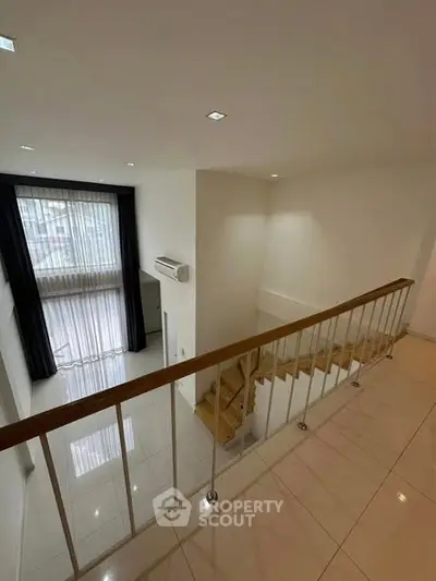 Spacious modern duplex with large windows and sleek staircase