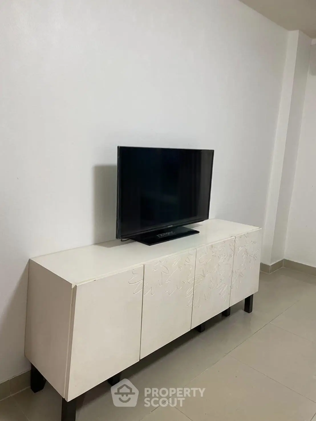Modern minimalist living room with sleek TV stand and flat-screen TV, perfect for contemporary living spaces.