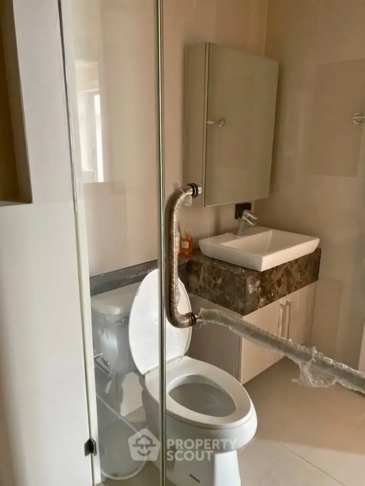 Modern bathroom with glass shower door and sleek vanity in a contemporary apartment.