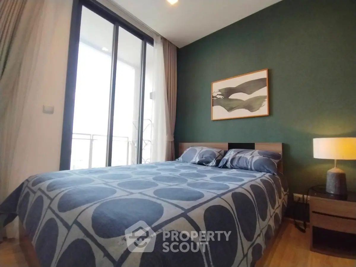 Modern bedroom with stylish decor and large window offering natural light.