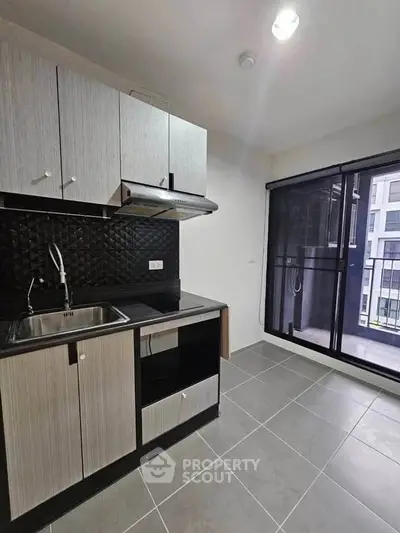 Modern kitchen with sleek cabinetry and balcony access in urban apartment.
