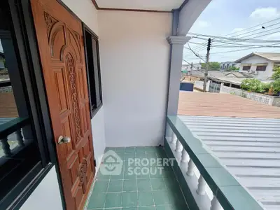 Charming balcony with wooden door and green tile flooring, offering a serene neighborhood view.