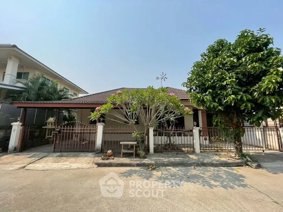 Charming single-story house with lush garden and gated entrance in a serene neighborhood.